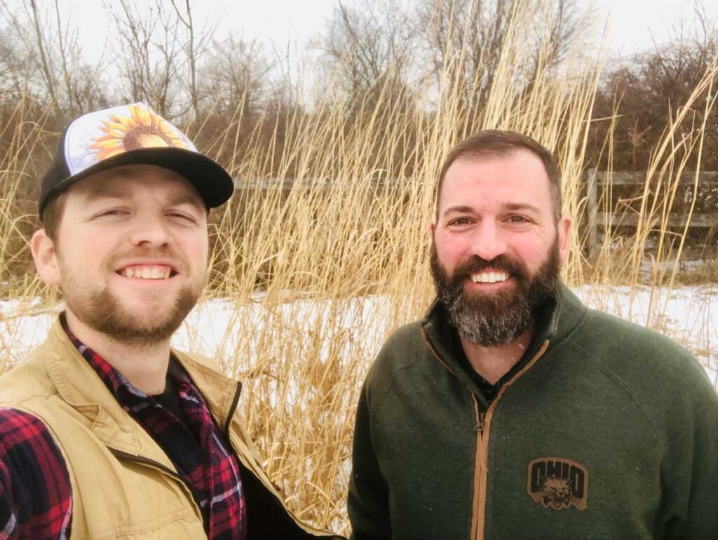 Nature Dads Brian and Jared, outside smiling together near a prairie in the winter